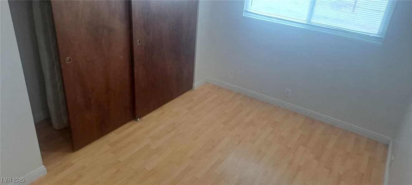 5231 Smoke Ranch Road Las Vegas, NV 89108 - Photo 12 of 23 Unfurnished bedroom with light wood-type flooring, a closet, and baseboards