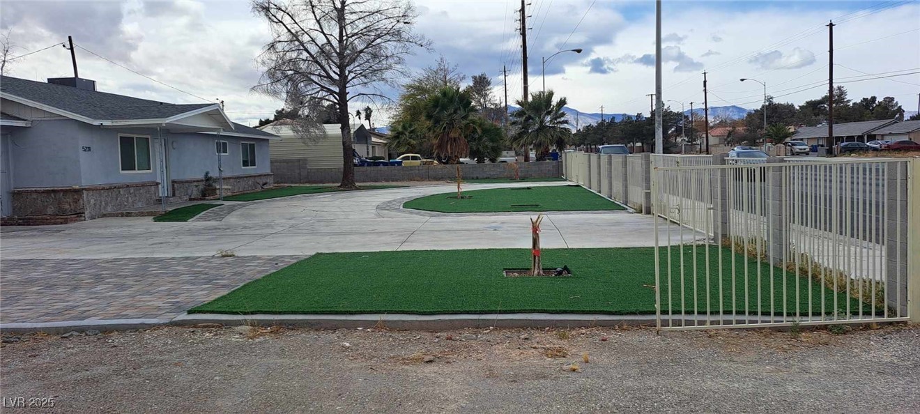 Surrounding community featuring fence, decorative driveway, and a yard