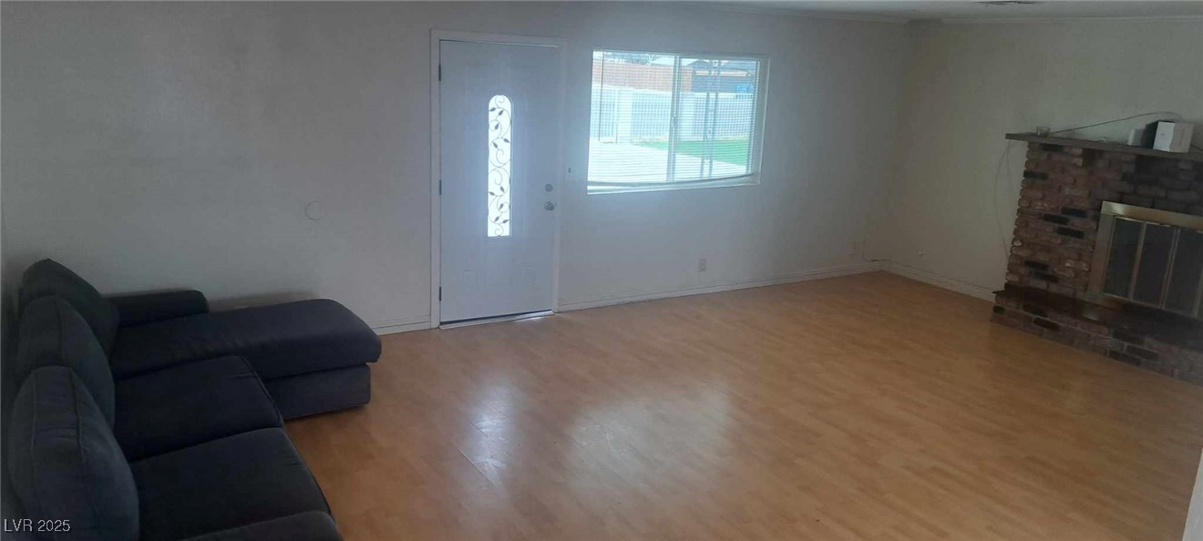 Living area featuring a brick fireplace, baseboards, and wood finished floors