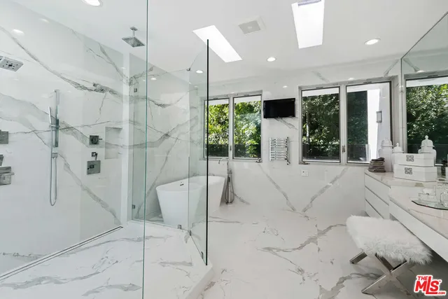 a large white kitchen with a large window and chandelier