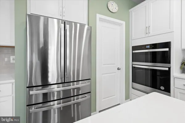 a large white kitchen with stainless steel appliances granite countertop a stove and a sink