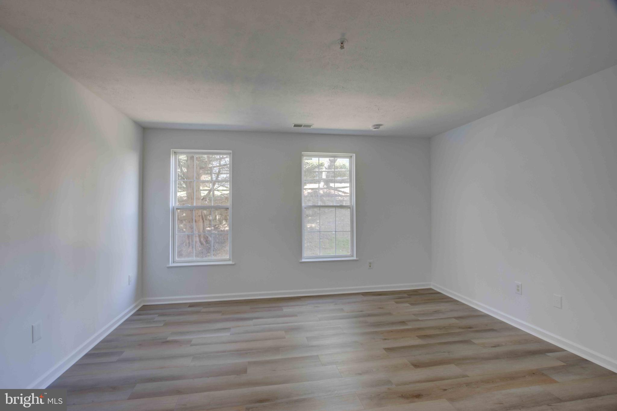 7903 Valley Manor Road, Unit 103 Owings Mills, MD 21117 - Photo 26 of 58 an empty room with wooden floor and windows