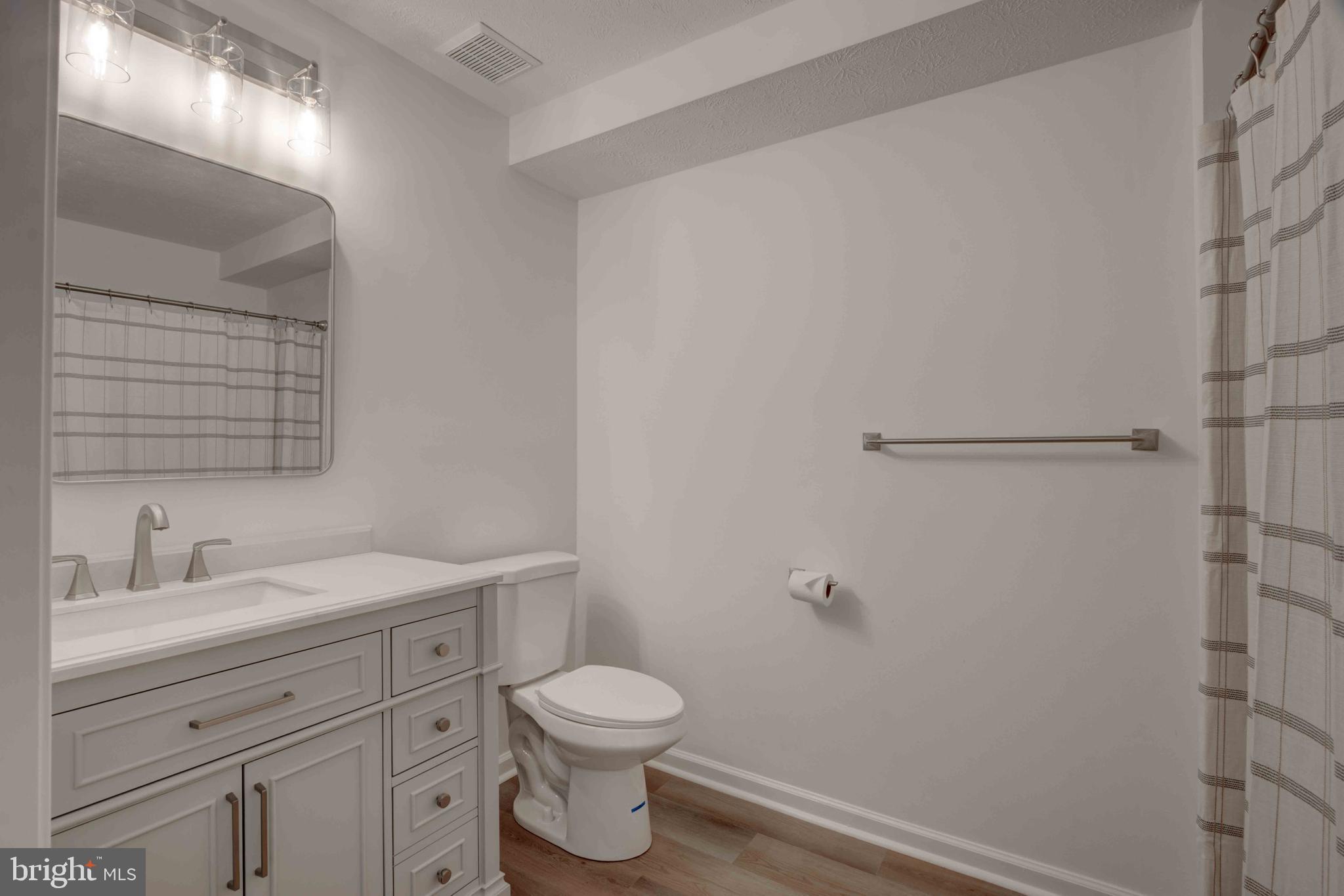 7903 Valley Manor Road, Unit 103 Owings Mills, MD 21117 - Photo 29 of 58 a bathroom with a toilet sink vanity and mirror