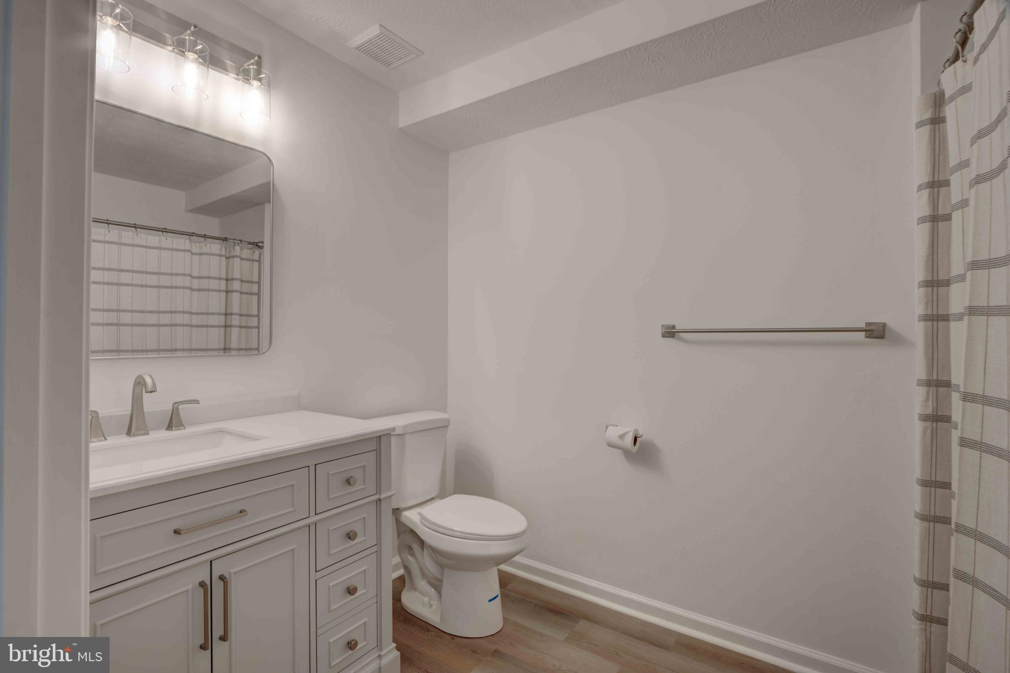 7903 Valley Manor Road, Unit 103 Owings Mills, MD 21117 - Photo 31 of 58 a bathroom with a toilet sink vanity and mirror