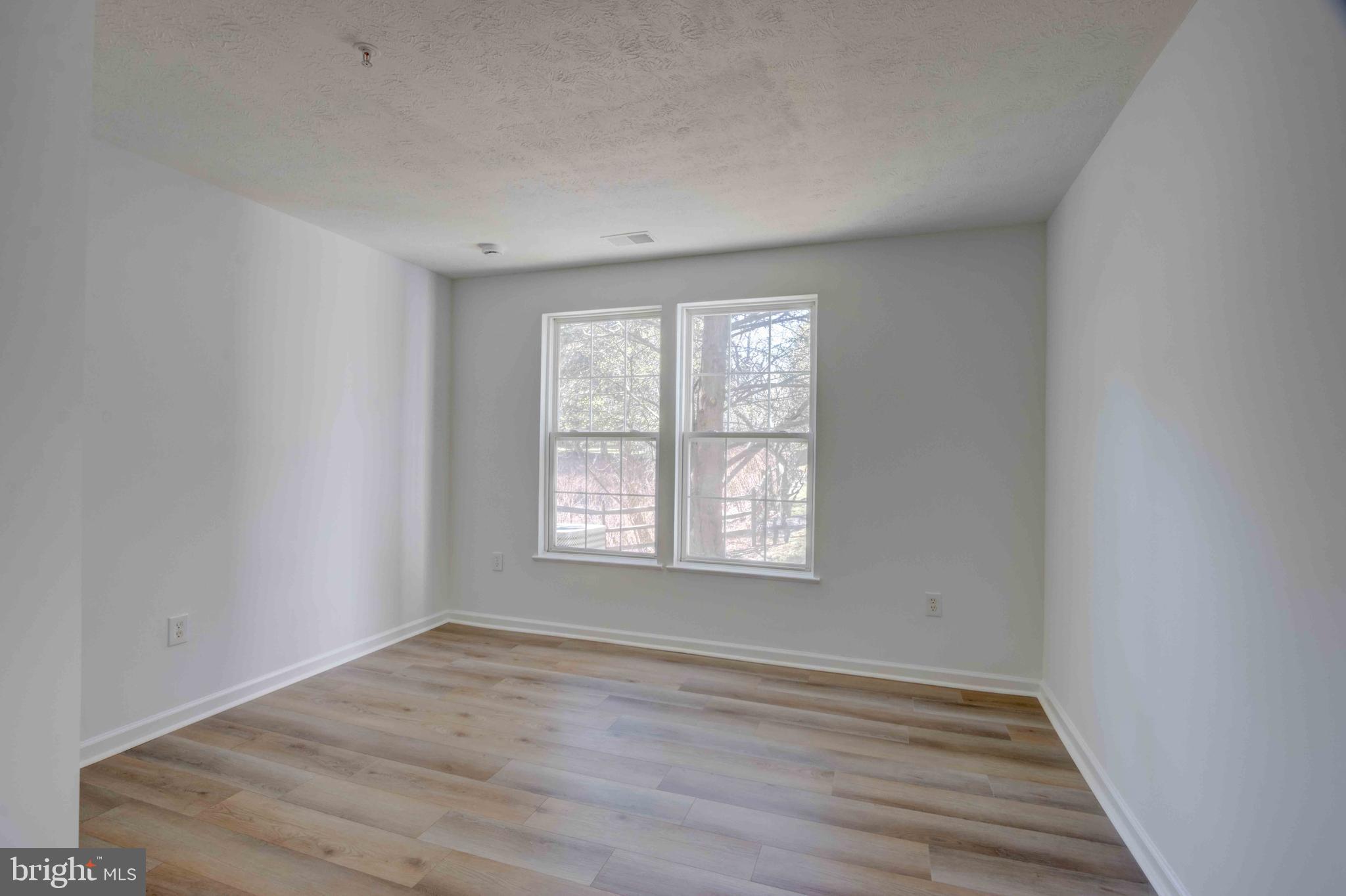 7903 Valley Manor Road, Unit 103 Owings Mills, MD 21117 - Photo 36 of 58 an empty room with wooden floor and windows