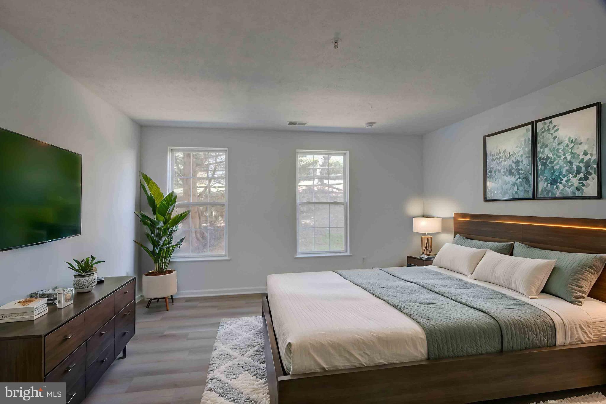 7903 Valley Manor Road, Unit 103 Owings Mills, MD 21117 - Photo 43 of 58 a bedroom with a large bed and a flat tv screen on dresser