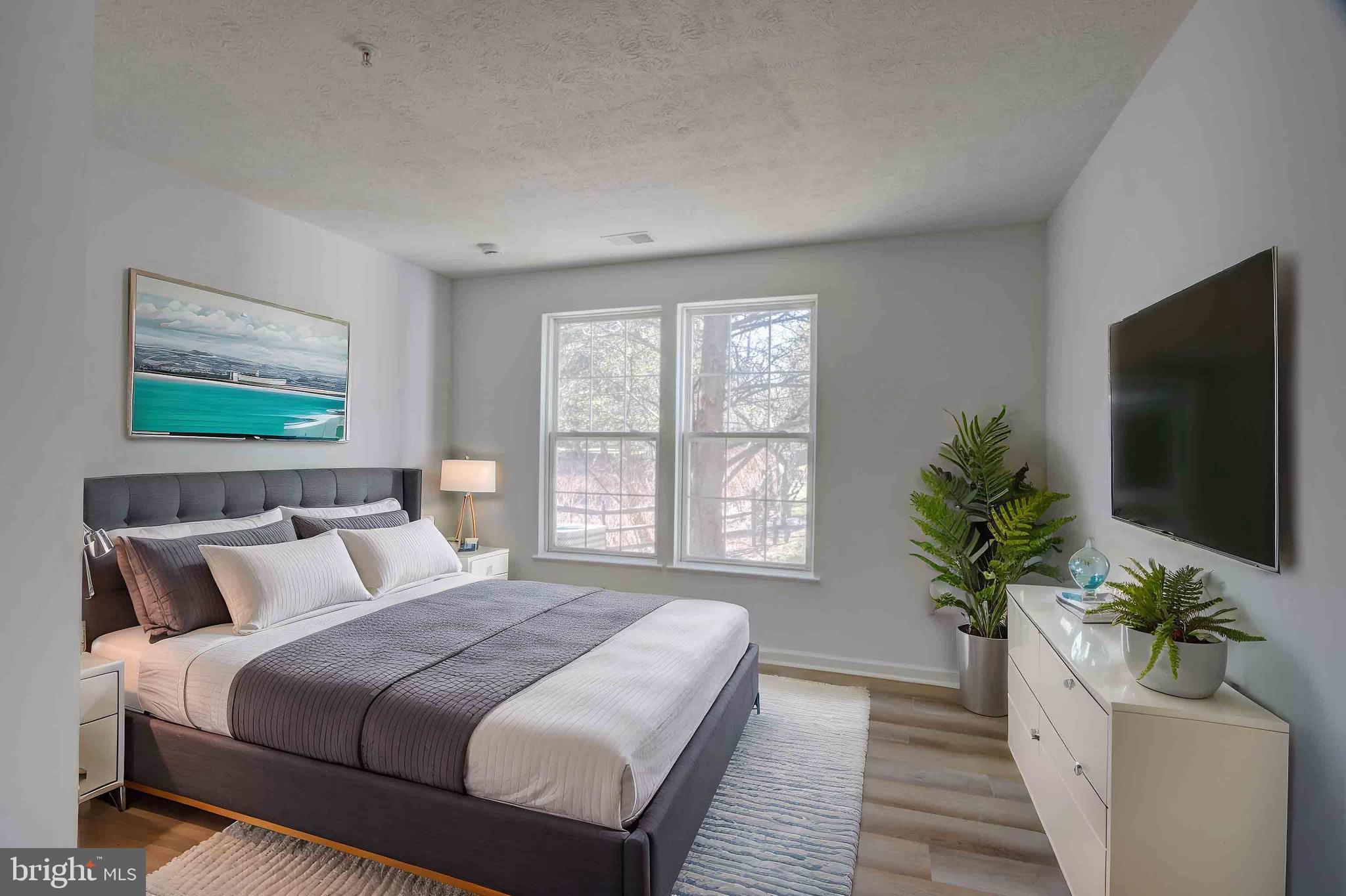 7903 Valley Manor Road, Unit 103 Owings Mills, MD 21117 - Photo 49 of 58 a bedroom with a large bed and a flat screen tv