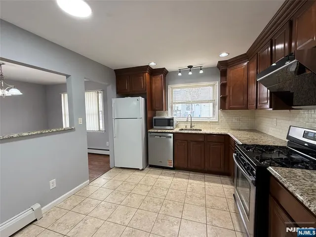 a kitchen with granite countertop a refrigerator and a stove top oven