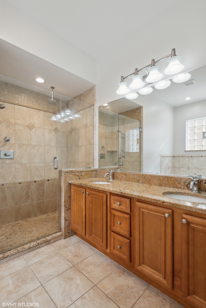 4417 South Calumet Avenue, Unit 2S Chicago, IL 60653 - Photo 10 of 16 a spacious bathroom with a granite countertop sink a mirror and a shower