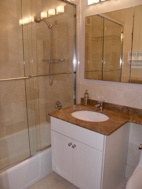 65 East India Row, Unit 22C Boston, MA 02110 - Photo 8 of 17 a bathroom with a granite countertop sink and a mirror
