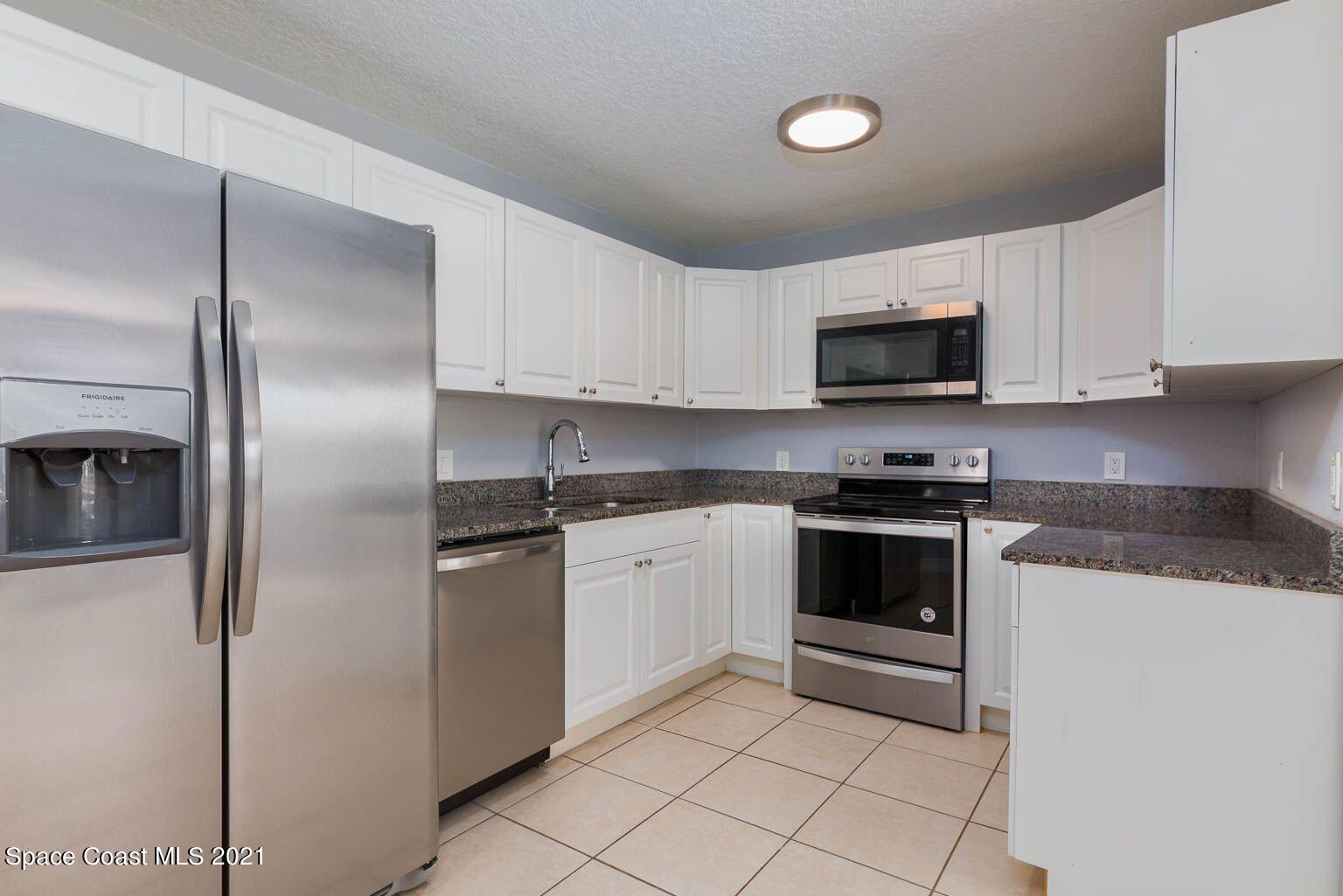 2648 Locksley Road Melbourne, FL 32935 - Photo 9 of 16 a kitchen with granite countertop white cabinets and stainless steel appliances