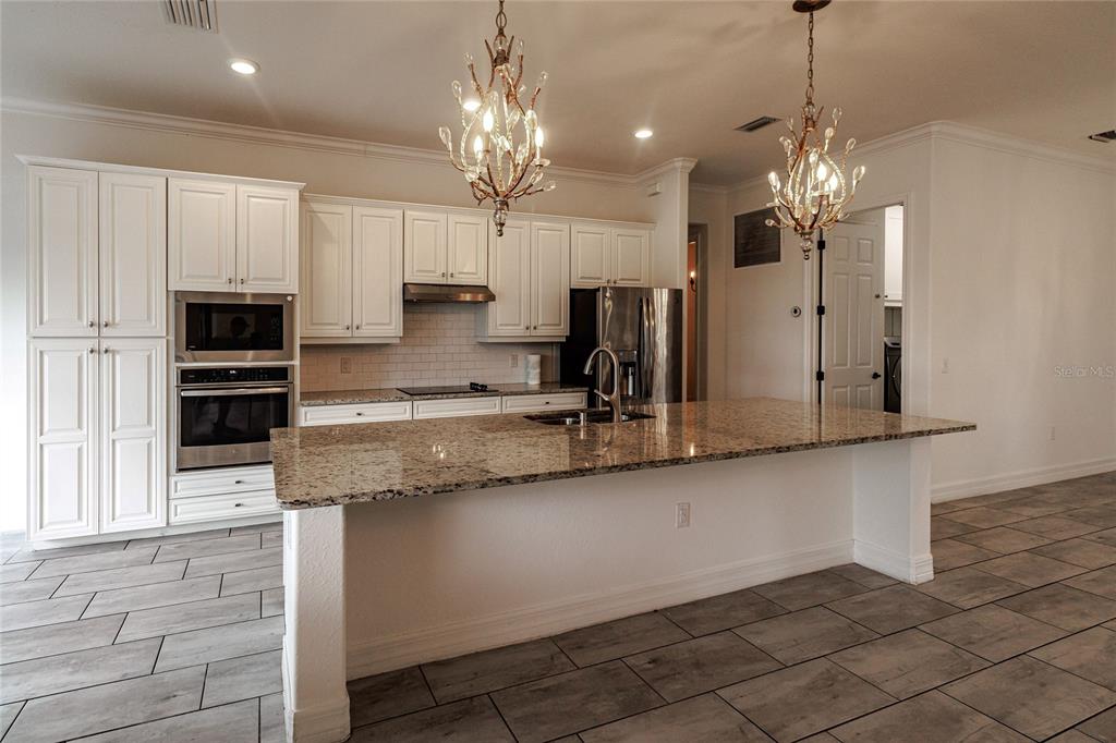 20315 Passagio Drive Venice, FL 34293 - Photo 8 of 40 a kitchen with stainless steel appliances granite countertop a sink refrigerator stove and microwave