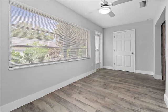 a view of an empty room with a window and wooden floor