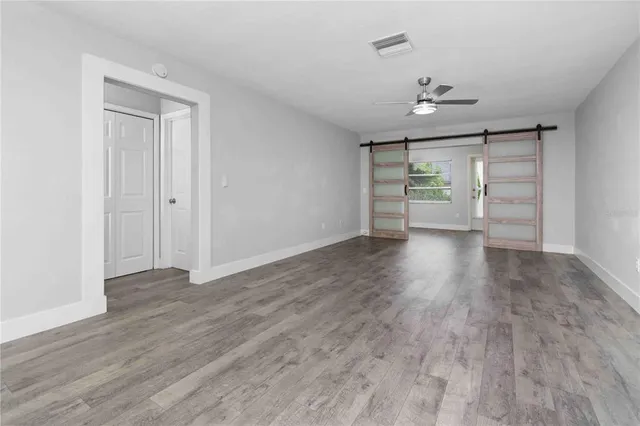 a view of an empty room with wooden floor and a window