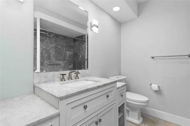 a bathroom with a granite countertop sink a toilet and a mirror