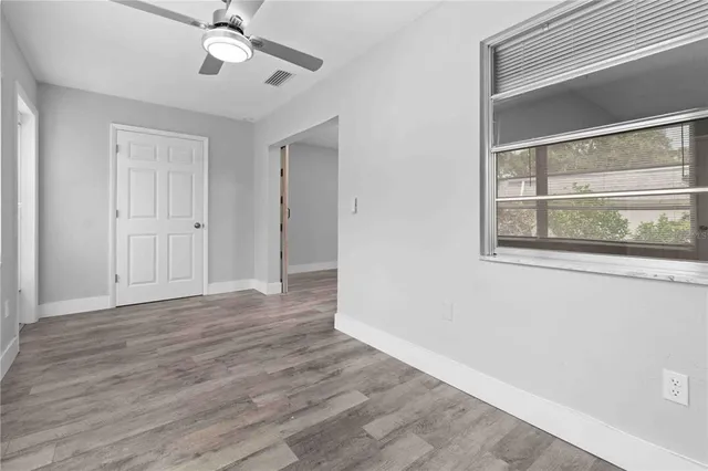 a view of empty room with wooden floor and fan