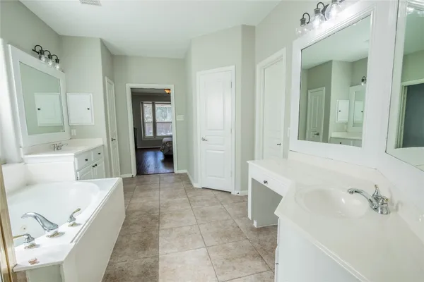 a large bathroom with a tub sink and mirror