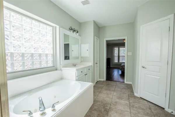 a spacious bathroom with a tub sink and mirror