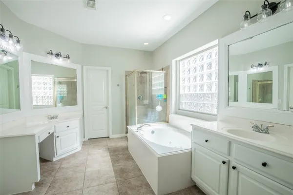 a spacious bathroom with a tub sink shower and mirror