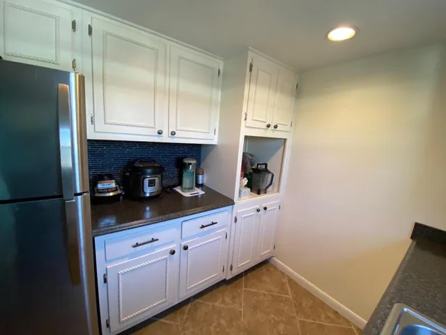 a kitchen with white cabinets and refrigerator