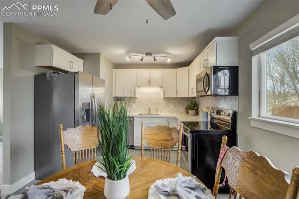 a kitchen with stainless steel appliances kitchen island granite countertop a refrigerator a stove top oven a sink with a dining table and chairs