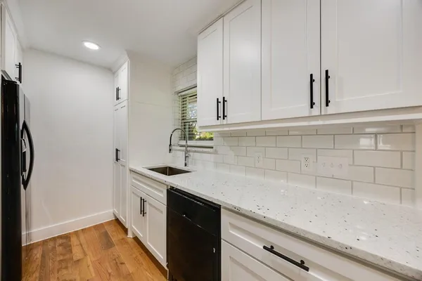 a view of empty room with wooden floor and kitchen view