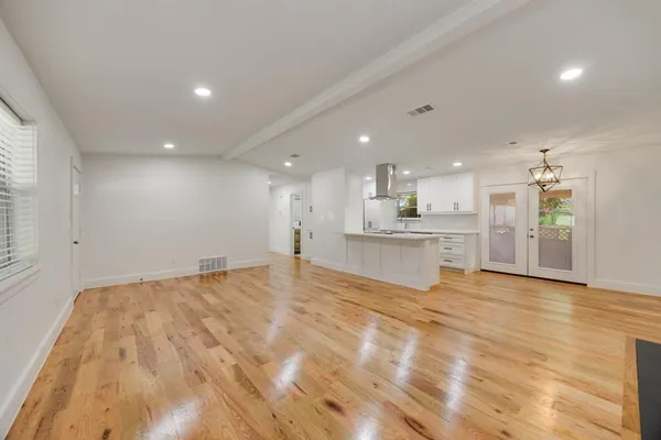 a view of an empty room with wooden floor and a fireplace