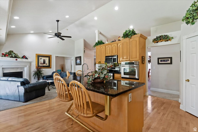 1924 North 2000th Street East Layton, UT 84040 - Photo 41 of 41 Kitchen featuring open floor plan, an island with sink, a kitchen bar, light wood-style floors, and lofted ceiling