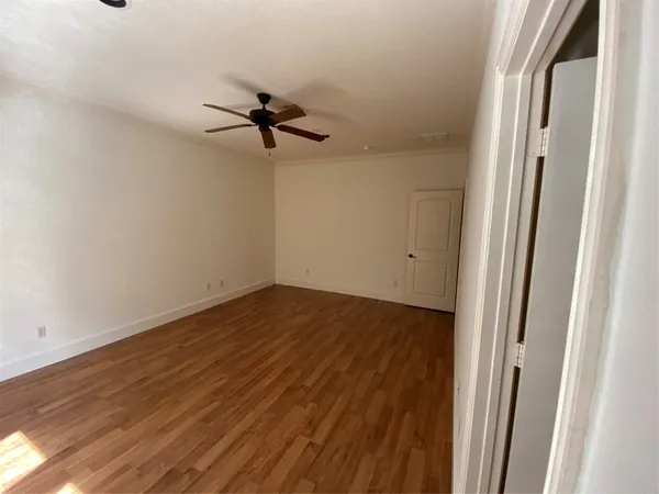 a view of a room with wooden floor and a ceiling fan