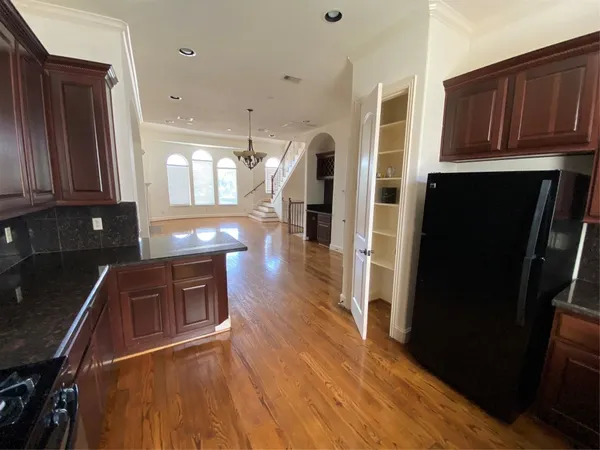 a kitchen with stainless steel appliances granite countertop a refrigerator a stove top oven and wooden floors
