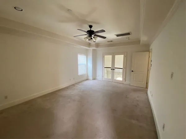 an empty room with a chandelier fan and windows