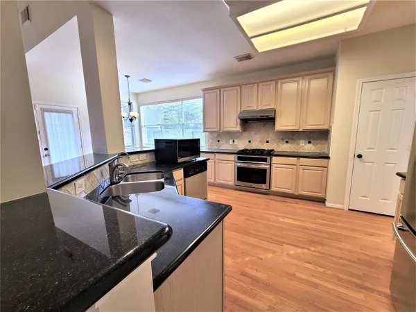 a kitchen with stainless steel appliances granite countertop a sink stove and refrigerator