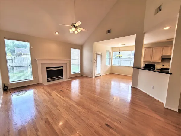 an empty room with wooden floor fireplace and windows