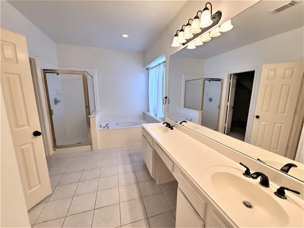 a spacious bathroom with a double vanity sink a mirror and a shower