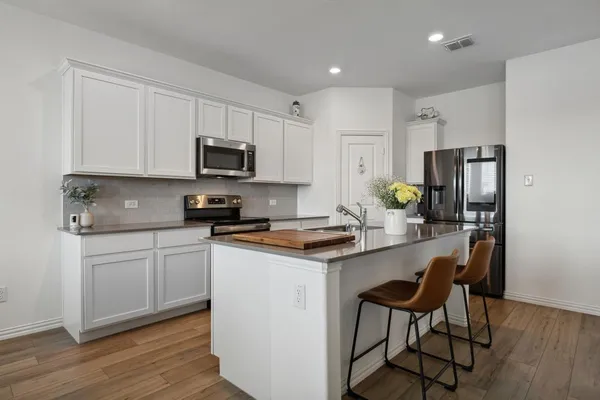 a kitchen with stainless steel appliances granite countertop a stove a sink a refrigerator and white cabinets