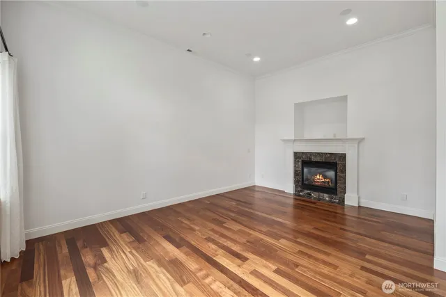 a view of an empty room with wooden floor a fireplace and a window