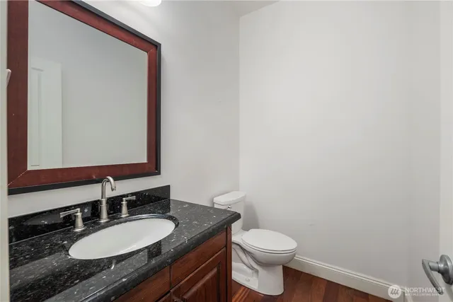a bathroom with a granite countertop toilet sink and mirror