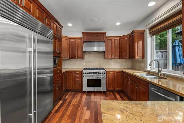 a kitchen with stainless steel appliances granite countertop a refrigerator a sink dishwasher a stove and white countertops with cabinets