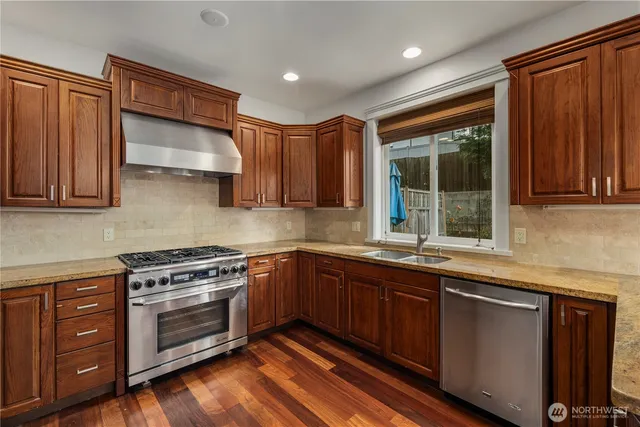 a kitchen with stainless steel appliances granite countertop wooden cabinets a sink and a stove