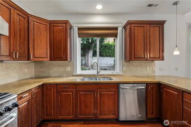 a kitchen with granite countertop wooden cabinets a sink and dishwasher