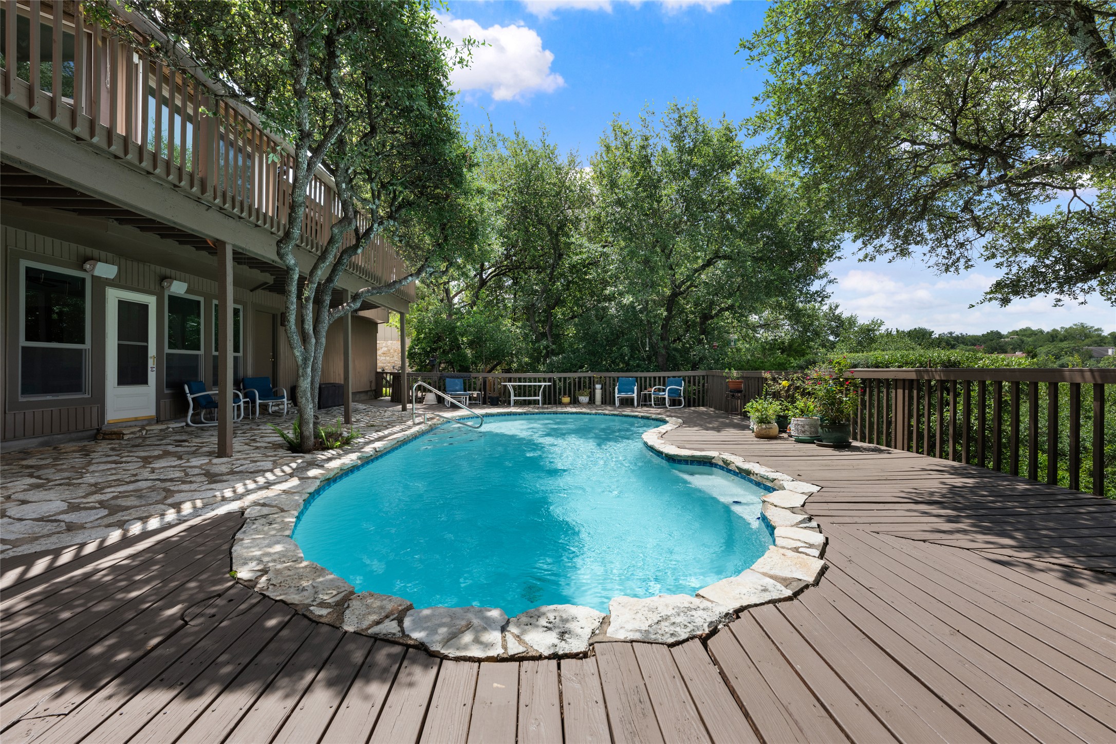 5319 Musket Ridge Austin, TX 78759 - Photo 32 of 39 An inviting backyard oasis offers a sparkling pool surrounded by a spacious wooden deck and lush greenery.