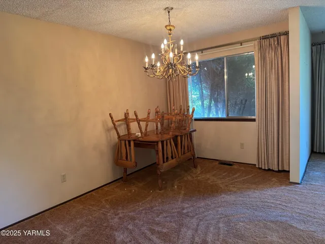 a view of a room with a chandelier and wooden floor