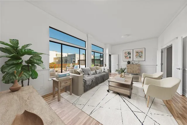 a living room with furniture a large window and wooden floor