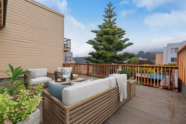 a roof deck with couches and potted plants