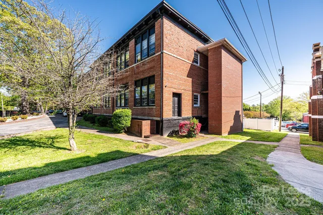 a front view of a building with garden and trees