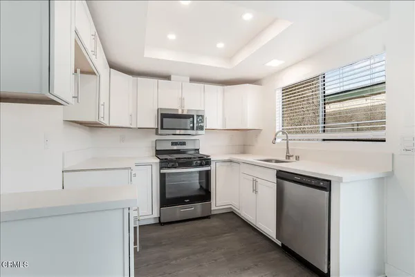 a kitchen with stainless steel appliances granite countertop a sink a stove a refrigerator and cabinets