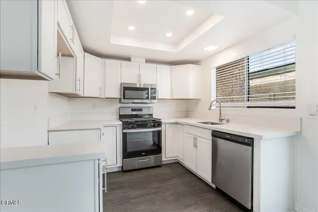 a kitchen with stainless steel appliances granite countertop a sink a stove a refrigerator and cabinets