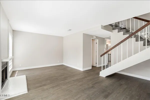 a view of an empty room with wooden floor and stairs