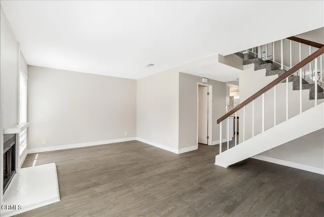 a view of an empty room with wooden floor and stairs