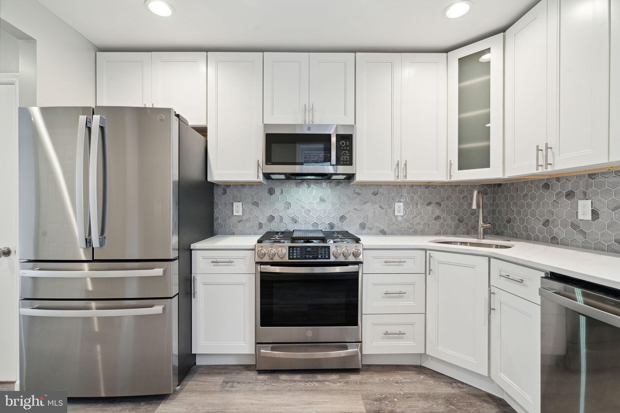 2033 Emily Street Philadelphia, PA 19145 - Photo 10 of 42 a kitchen with white cabinets and stainless steel appliances
